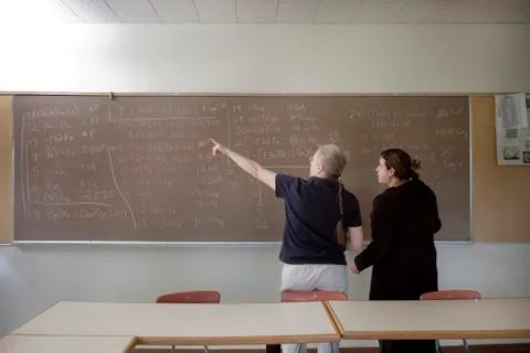 Teacher explaining arithmetic to student in classroom Stock Photos