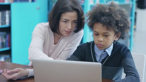 Teacher explaining boy how to do task on laptop Stock Footage 108746238