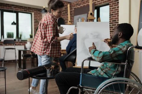 Teacher explaining illustration process to paralyzed student with disability Foto stock