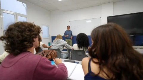 Teacher explaining a lesson to university students in a classroom Stock Footage 337035513