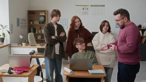 Teacher Explaining Material to Group of Students Gathered Around Laptop Stock Footage 335694269