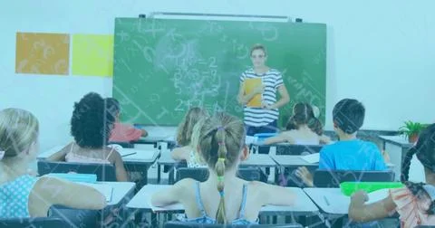 Teacher explaining math on chalkboard to children, wearing striped top and Stock Photos