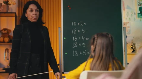 Teacher explaining a math equation near the chalkboard to noisy pupils Stock Footage 303139021