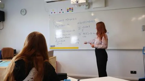 Teacher explaining math equations to student in classroom Stock Photos