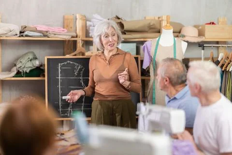 Teacher explaining pattern structure by chalkboard during sewing course for 스톡 사진