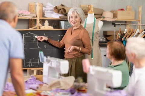 Teacher explaining pattern structure by chalkboard during sewing course for 스톡 사진