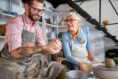 Teacher explaining to student how to model a clay pot on workshop. Creative.. Stock Photos