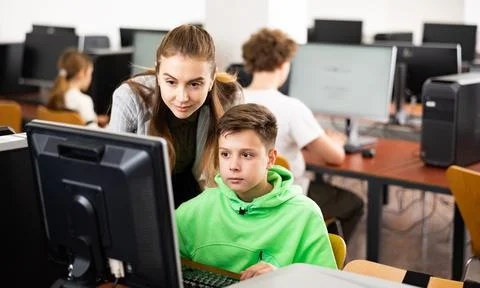 Teacher explaining task solution to pupil during computer science lesson Stock Photos