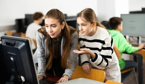 Teacher explaining task solution to pupil during computer science lesson Foto stock