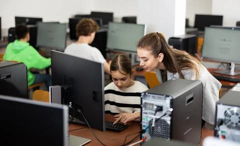 Teacher explaining task solution to pupil during computer science lesson Foto stock