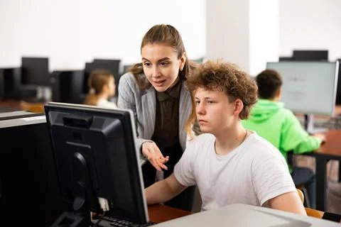 Teacher explaining task solution to pupil during computer science lesson Foto stock