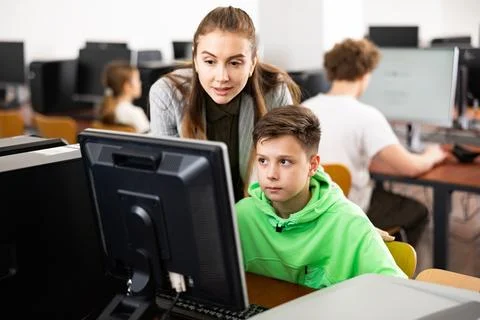 Teacher explaining task solution to pupil during computer science lesson Stock Photos