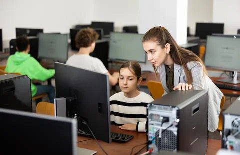 Teacher explaining task solution to pupil during computer science lesson Stock Photos