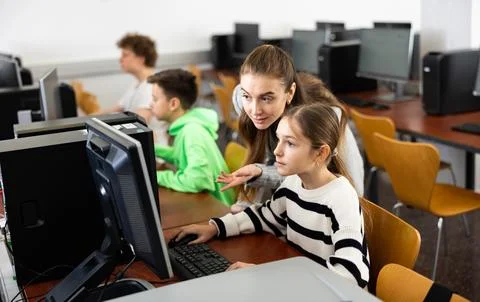 Teacher explaining task solution to pupil during computer science lesson Foto stock