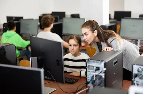Teacher explaining task solution to pupil during computer science lesson Foto stock