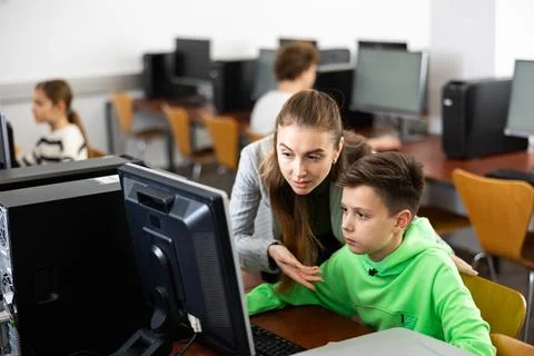Teacher explaining task solution to pupil during computer science lesson Foto stock