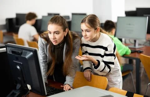Teacher explaining task solution to pupil during computer science lesson Fotos Stock