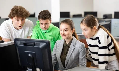 Teacher explaining task solution to surprised students in computer class Stock Photos