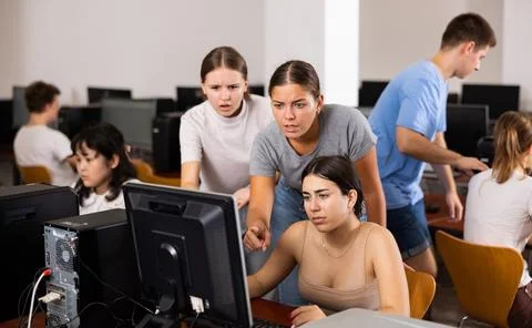 Teacher explaining task solution to young girl and boys during computer science Stock Photos