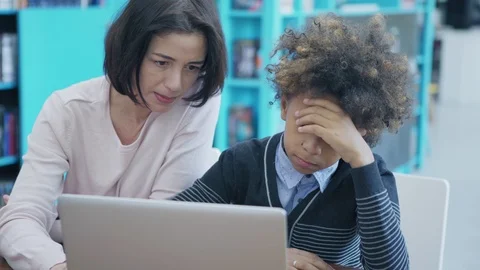 Teacher explaining to upset boy how to work on laptop Stock Footage 108746255