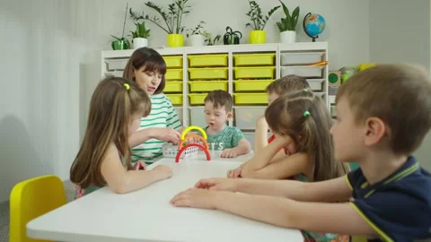 The teacher explains and shows the task to a group of children. Vídeos de archivo 245203784