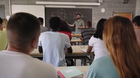 The teacher explains the lesson on the blackboard in the background while in the Stock Footage 221789090