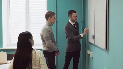 Teacher explains something on a whiteboard to students Stock Footage 85048715