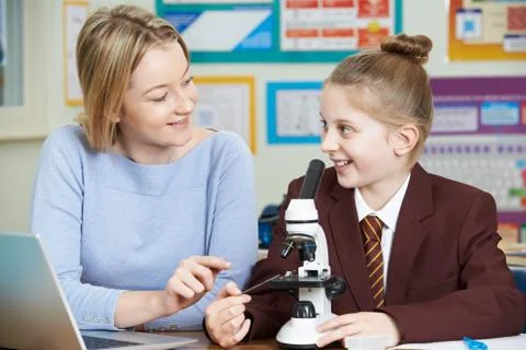 Teacher With Female Student Using Microscope In Science Class Stock Photos
