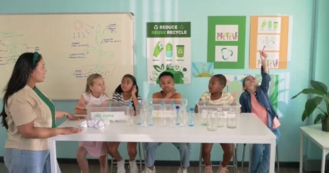 Teacher with five students asking about recycling at long white table, group Stock Footage 340964474