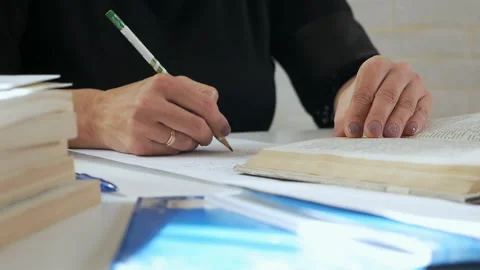 The teacher flips through the book, makes extracts from the book. A woman reads 스톡 동영상 117296164