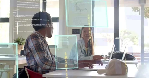 Teacher gesturing to laptop in tech lab initiating code overlays as students Stock Footage 317858061