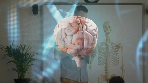 Teacher gesturing at skeleton, brain and DNA floating over desks while class Stock Footage 328233158