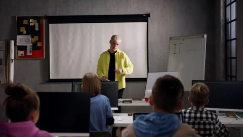 Teacher giving computer science lecture to young students in dark room. Room Stock Footage 186895217