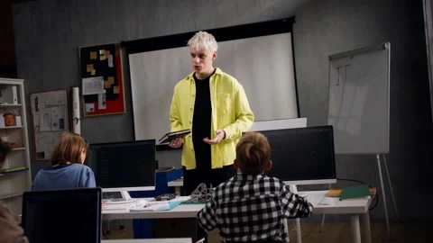 Teacher giving computer science lecture to young students in dark room. Room Stock Footage 196908139