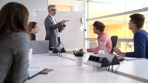 Teacher giving economics class, using whiteboard Stock Footage 86617168