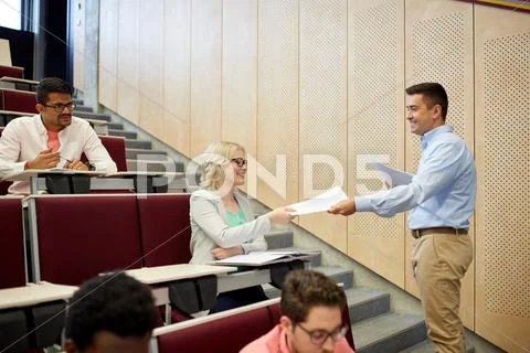 Teacher giving tests to students at lecture Stock Photos