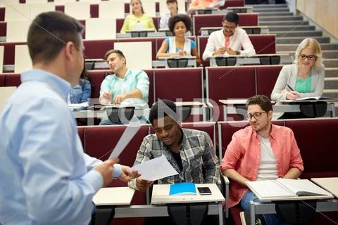 Teacher giving tests to students at lecture Stock Photos