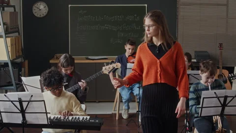 Teacher Going around Class and Listening to Kids Playing Instruments Видео 280258475