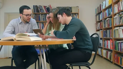 Teacher with group of students working on digital tablet in library Stock Footage