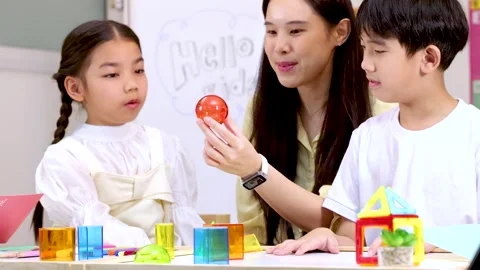 Teacher Guides Children Learning Geometry With Colorful Blocks in Classroom Stock Footage 330101972