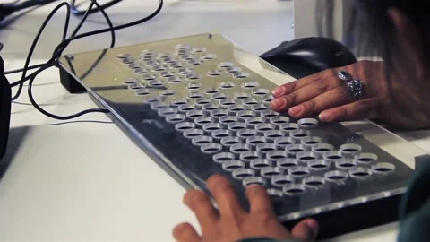 Teacher Guiding a Blind Student Using a Tactile Keyboard in Computer Class Stock Footage 105443118