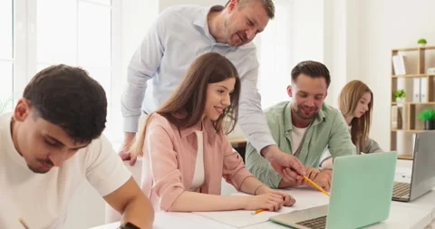 Teacher guiding college students during classroom lesson with laptops and notes Stock Footage 337560124