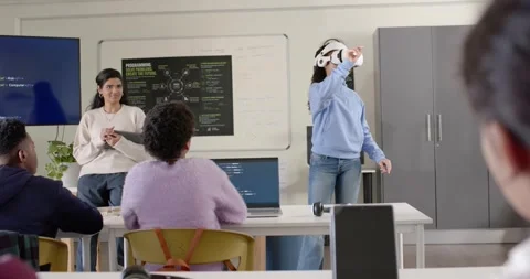 Teacher guiding demo while youth putting on VR headset reaching interacting with Stock Footage 341063477
