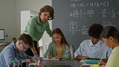 Teacher Guiding Students, Diligently Working on Math Problems in Classroom Stock Footage 316628329