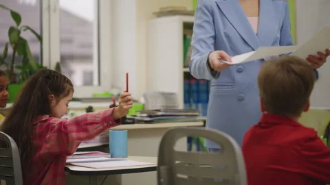 Teacher handing out graded test papers to primary school students Stock Footage 335683726