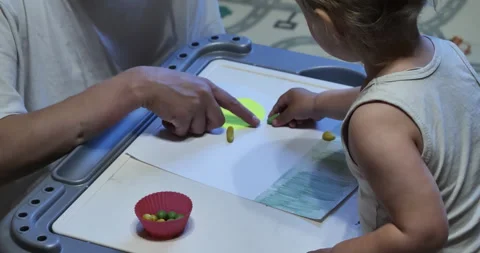 Teacher Hands Engaging with Toddler Sorting Playdough Shapes on Colorful Drawing Stock Footage 242224901
