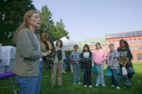 Teacher with hawk on her arm addressing students during Earth Day event in Stock-Fotos