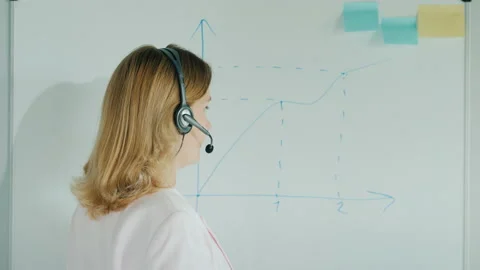 Teacher in headset draws graph on board Stock Footage 136106561