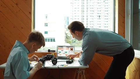 Teacher help student fixing car model and giving advise at class. Edification. Stockfoto's