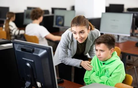 Teacher helping boy to solve computer problem Stockfoto's